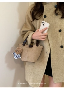 Nahaufnahme der Retro-Eimertasche in Camel mit braunen Griffen und Teddy-Anhänger