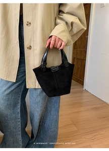 Detail der schwarzen Wildleder-Eimertasche mit Lackledergriffen getragen zum beigen Trenchcoat