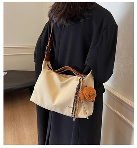 Detail of beige canvas tote with brown leather strap and cute teddy bear charm