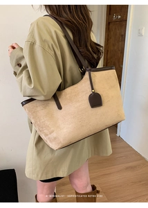 Détail du grand cabas en daim kaki avec finitions en cuir marron porté par un mannequin
