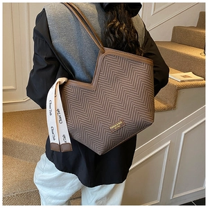Detail of vintage brown herringbone tote bag with decorative silk scarf and metal logo