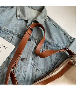 Detail of adjustable leather strap and metal buckle on canvas crossbody tote bag