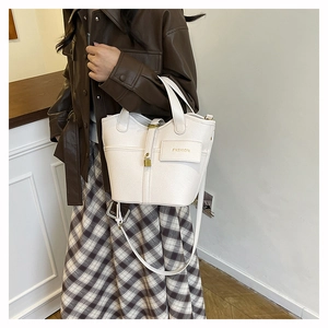 Detail of cream white pebbled leather bucket bag with gold lock and detachable strap
