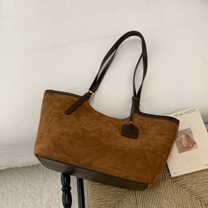 Détail d'un sac cabas en daim marron avec bordure en cuir et bandoulière réglable