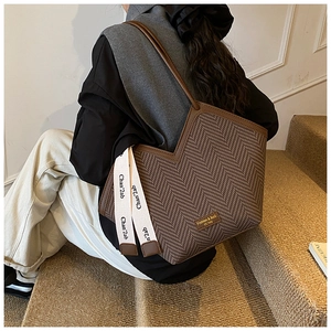 Detail of vintage brown tote bag with herringbone texture and long leather shoulder straps
