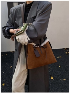 Dettaglio borsa a tracolla scamosciata marrone con bordo in shearling bianco e fiocco