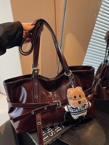 Dark red patent leather tote bag with decorative buckle and plush puppy charm