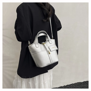 Detail of silver bucket bag with litchi grain texture and gold fashion lock buckle