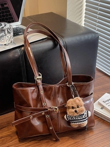 Dark brown patent leather tote bag with a plush bear charm and metallic buckle details