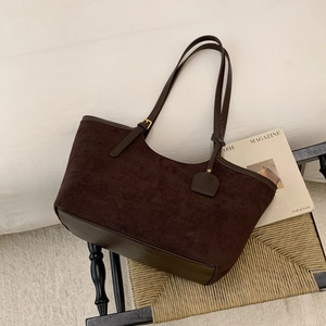 Vue détaillée du sac cabas en daim marron café avec ferrures dorées sur une chaise