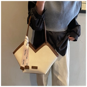 Detail of woven tote bag with V-shaped opening and silk scarf on leather handles