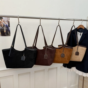Sacs cabas minimalistes en daim noir, café et beige suspendus sur un support métallique