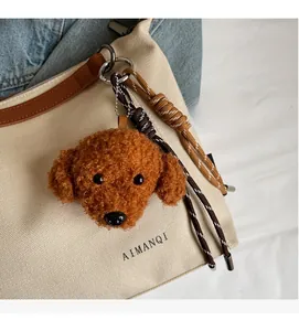 Close-up of a brown plush poodle charm with a braided strap on a canvas tote bag