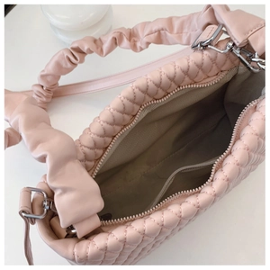 Detail of pink quilted handbag showing interior zipper pocket and stitched lining