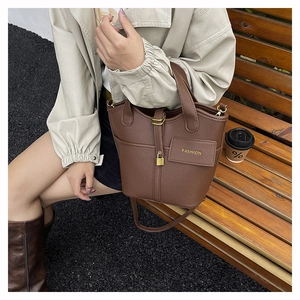 Detail of deep brown lychee grain bucket bag with gold lock charm and fashion logo