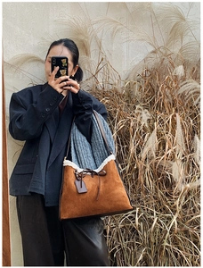Dettaglio della borsa tote in pelle scamosciata con bordo in shearling sintetico e fiocco