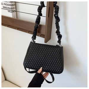 Detail of black quilted leather shoulder bag featuring unique ruffled scrunchie strap design