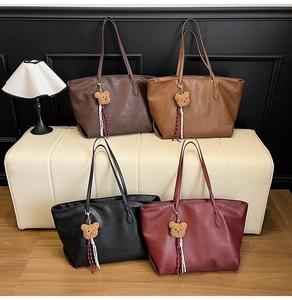 Detail of four retro tote bags in brown, caramel, black, and burgundy with bear charms