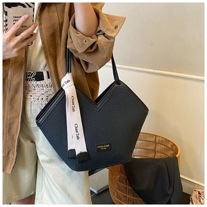 Detail of black woven tote bag with V-shaped cut and decorative lettered strap