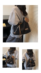 Detail of adjustable leather strap and side zipper on a large black canvas tote bag