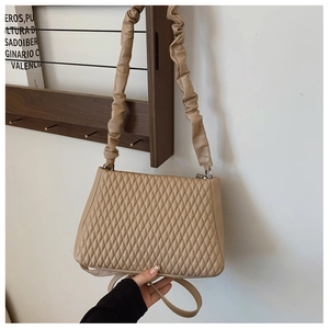 Detail of beige quilted shoulder bag featuring a ruched cloud-style strap and smooth texture
