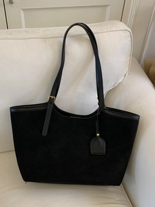 Sac fourre-tout noir minimaliste en suédine avec garniture en cuir sur un canapé blanc