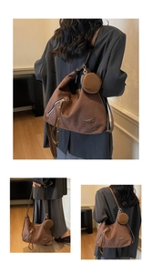 Detail view of brown suede crescent tote bag with fashion label and small round pouch