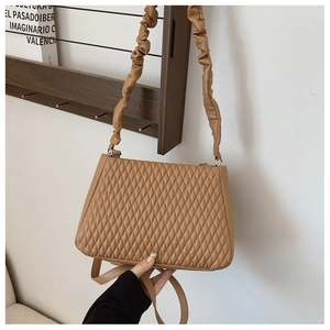 Detail of caramel quilted hobo bag with scrunched handle and adjustable strap