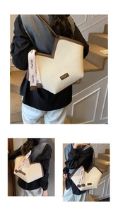 Detail view of large tote bag with herringbone weave, brown leather trim and v-cut top