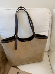 Grand sac cabas vintage en daim kaki avec bordures en cuir marron sur un canapé