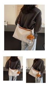 Detail of white canvas tote bag with brown leather trim and cute teddy dog charm