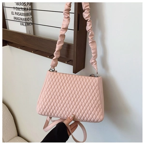 Close-up of pink quilted crossbody bag with stylish cloud-like pleated handle detail