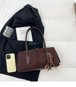 Détail du sac bandoulière en daim marron foncé avec fermetures éclair dorées