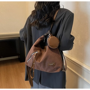Detail view of large brown suede tote bag with round coin purse and metal side zipper