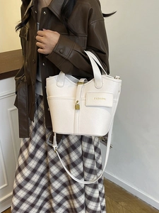 Minimalist beige bucket bag with gold lock detail and adjustable strap for women