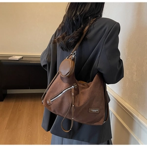 Detail view of brown suede hobo bag with fringe zipper and small round coin purse charm