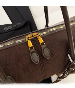 Détail des fermetures éclair dorées sur un sac Boston vintage marron foncé mat