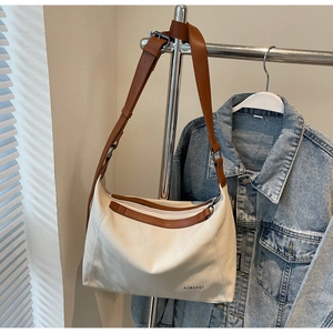 Detail of adjustable brown leather strap and zip closure on cream canvas tote bag