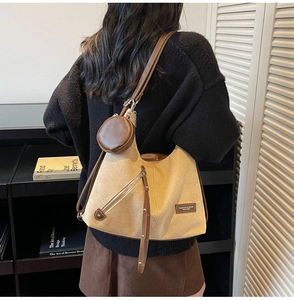 Detail of beige canvas tote with brown leather trim, fringe zipper, and coin pouch accessory