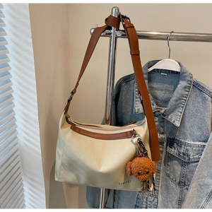 Canvas tote with brown leather trim, adjustable strap, and cute plush puppy charm