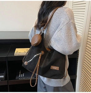 Detail of a black canvas tote with brown leather trim and a detachable round pouch
