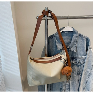 Detail of canvas tote with brown leather strap and cute plush puppy charm accessory