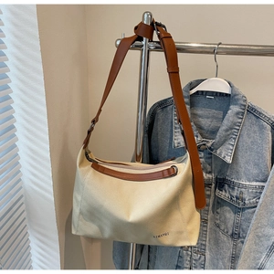 Detail of canvas tote bag with brown leather straps and AIMANQI logo lettering