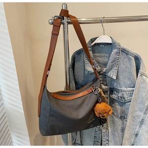 Detail of grey canvas tote bag with brown trim and cute plush bear charm accessory