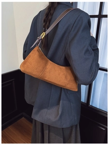 Detail of brown faux suede underarm bag with contrast stitching and golden metal buckle