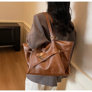 Detail of vintage brown tote bag showing adjustable buckle strap and oily leather texture