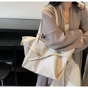 Detail of a creamy white leather tote bag with lychee texture and golden hardware accents