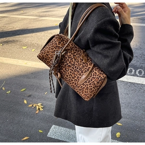 Gros plan du sac Boston léopard avec bandoulières en cuir sur un blazer gris