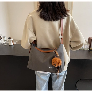 Detail of grey canvas tote with brown leather straps and plush bear charm decoration