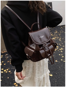 Dark brown faux leather backpack with flap drawstring closure and multi-pockets on model